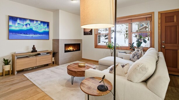 A living room with a fireplace, a sofa, a coffee table, and a painting of the Northern Lights.