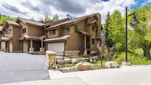 A multi-story log cabin-style building with a garage, stone foundation, and a well-maintained lawn.