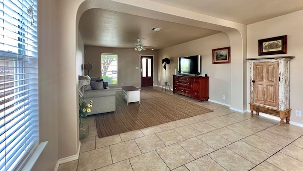 A spacious living room with a large window, a sofa, a coffee table, a TV, and a wooden cabinet.