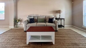 A living room with a beige sofa, a wooden coffee table, and a small side table with a lamp.