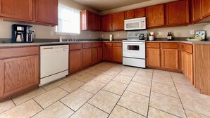 A kitchen with wooden cabinets, a microwave, an oven, a dishwasher, and a coffee maker.