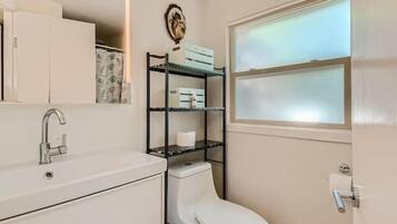 A compact bathroom with a white sink, a toilet, and a window.