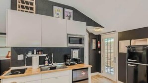 A compact kitchen with white cabinets, a microwave, a coffee maker, and a dishwasher.