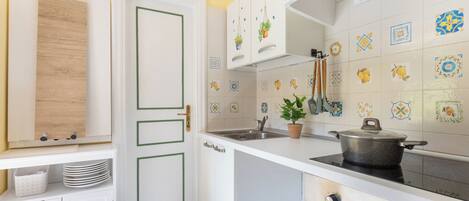 Een koelkast, een oven, een kookplaat, kookgerei, borden en bestek