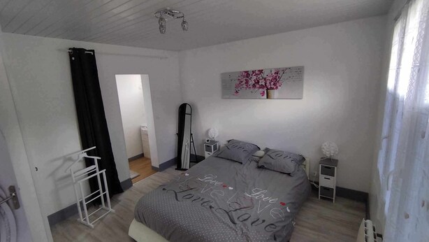 Une chambre à coucher avec un lit, un miroir, une commode, une table de chevet et un tableau accroché au mur.