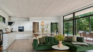 A modern living room with a green sofa, a round coffee table, and a dining area with a wooden table and chairs. - Beautiful home in Frederiksværk (Frederiksværk)