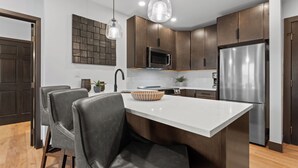 Una cucina moderna con mobili in legno scuro, un frigorifero in acciaio inossidabile, un forno a microonde e luci a sospensione.