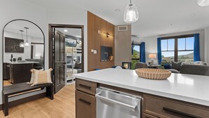 Una cucina moderna con isola centrale, rivestimenti in legno e vista sull'area soggiorno.