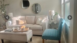 A living room with a beige sofa, a blue armchair, a coffee table, and two round mirrors on the wall.