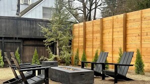 A patio area with a fire pit, black Adirondack chairs, and a wooden fence. - Camas Lakehouse With Private Hot Tub (Camas)