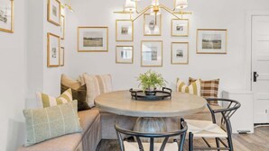 A dining area with a round table, chairs, a chandelier, and framed pictures on the wall. - Camas Lakehouse With Private Hot Tub (Camas)
