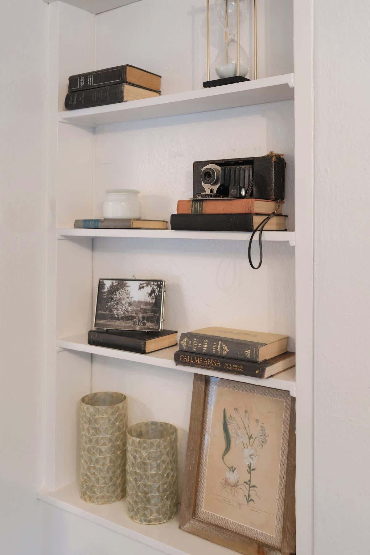 A bookshelf with books, a camera, a picture frame, and decorative items.