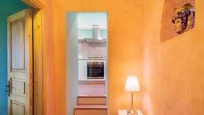 A staircase leading to a kitchen with a stove and oven, a lamp on a small table, and a door on the left. - Lunarosa, scenic country cottage in Montargano. (Mascali)