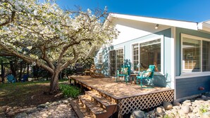 Un patio couvert avec des meubles d’extérieur, une terrasse en bois et une vue sur une maison dotée de grandes fenêtres.