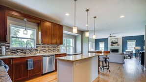 Una cocina moderna con armarios de madera, una isla grande e iluminación colgante.