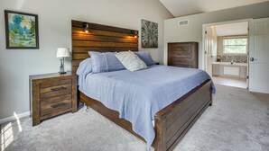 Un dormitorio con cama de madera, mesita de noche, cómoda y un cuadro en la pared.