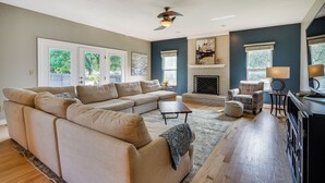 Una sala de estar con un sofá seccional color beige, una chimenea y un comedor con mesa y sillas.