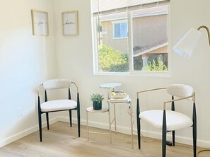 Relax in a stylish room with a large window offering a view of the outside, a comfortable seating area, and a floor lamp.