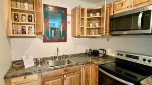 A kitchen with wooden cabinets, a stainless steel microwave, a stove, and a granite countertop.
