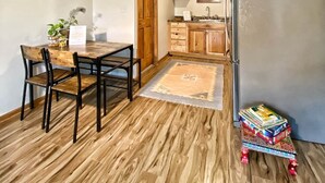A compact kitchen with wooden cabinets, a stainless steel refrigerator, and a dining area with a wooden table and chairs.