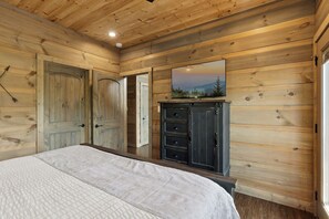 Une chambre à coucher avec un lit, une commode et un téléviseur fixés sur un mur en bois.