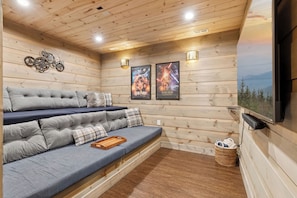 A cozy room with a sofa, wall-mounted posters, and a television.