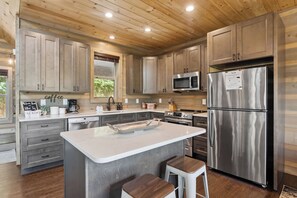 Una cocina moderna con armarios de madera, electrodomésticos de acero inoxidable y una isla central con taburetes.