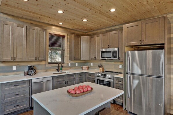 Una cocina moderna con armarios de madera, electrodomésticos de acero inoxidable y una isla central con un frutero.