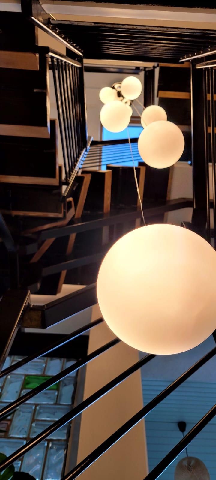 Eine moderne Treppe mit schwarzen Geländern und einer Reihe von kugelförmigen Leuchten.
