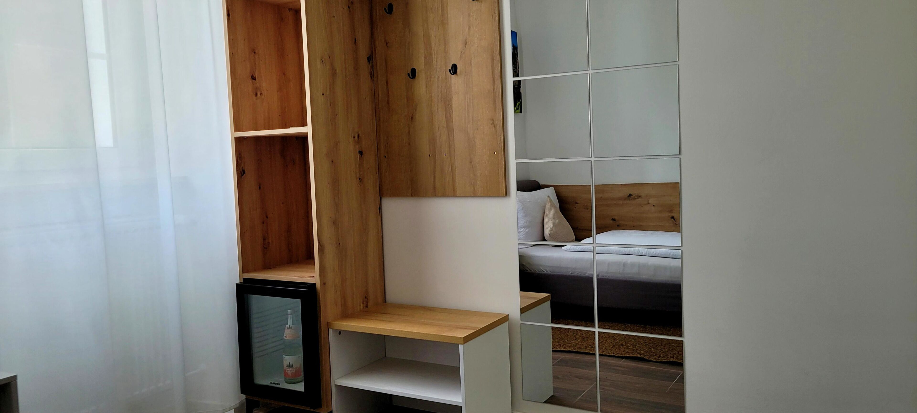 A compact room with a bed, a small shelf unit, and a television.