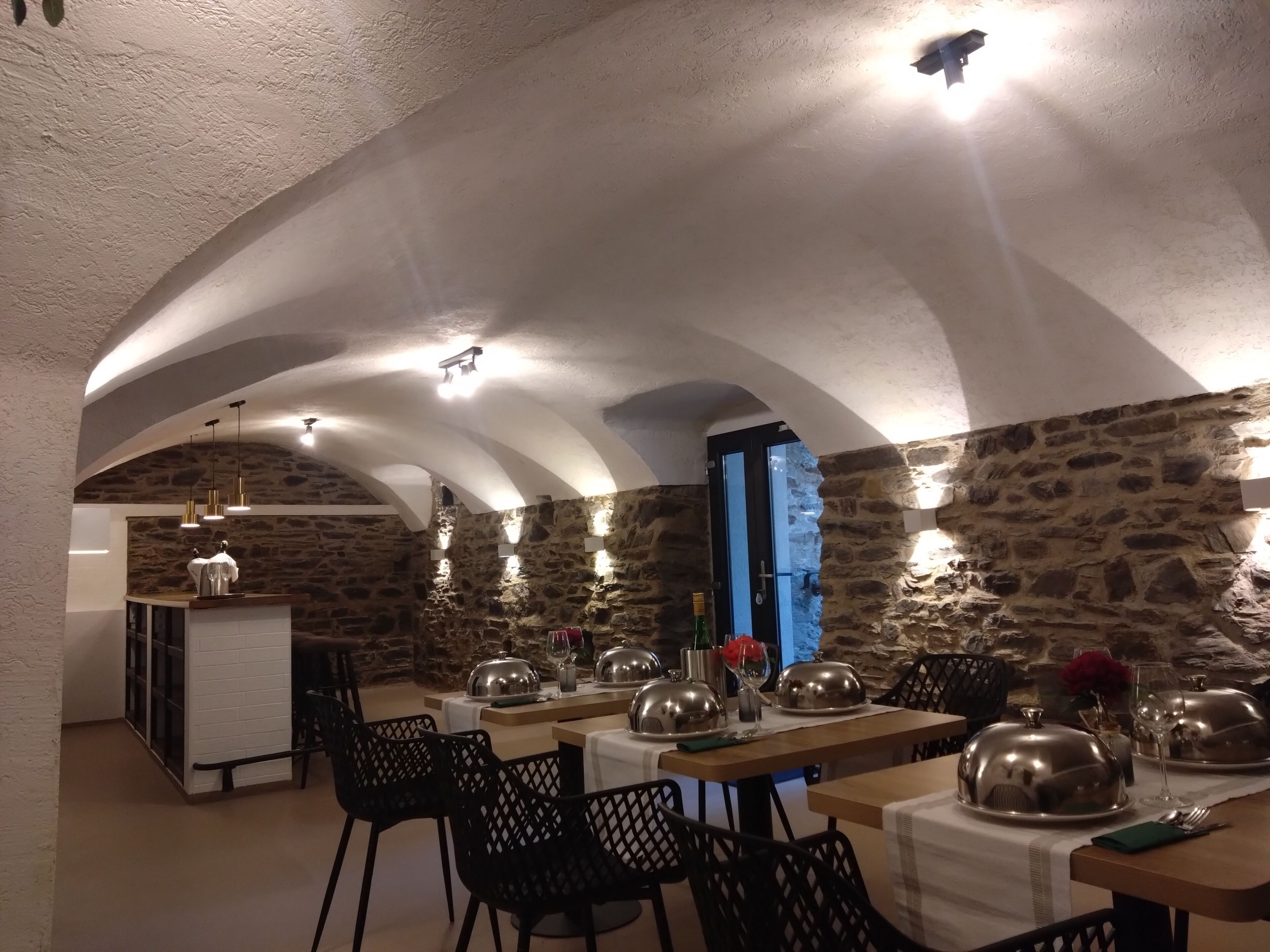 A restaurant with stone walls, arched ceilings, and tables set for dining.