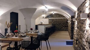 A dining area with a stone wall, wooden tables, and black chairs. - MoselVilla No 7 (Pommern)