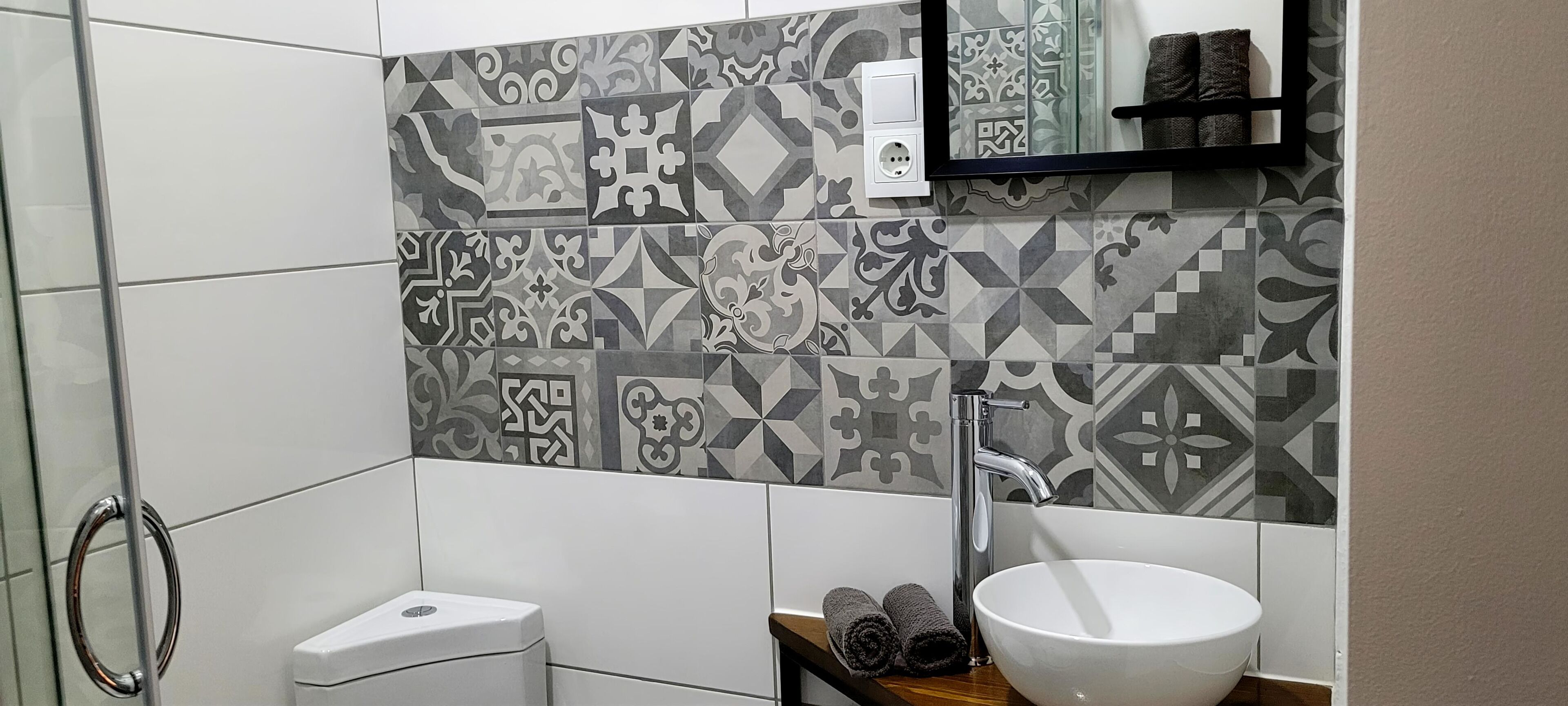 Un baño con baldosas estampadas, un lavabo blanco y un perchero para toallas.