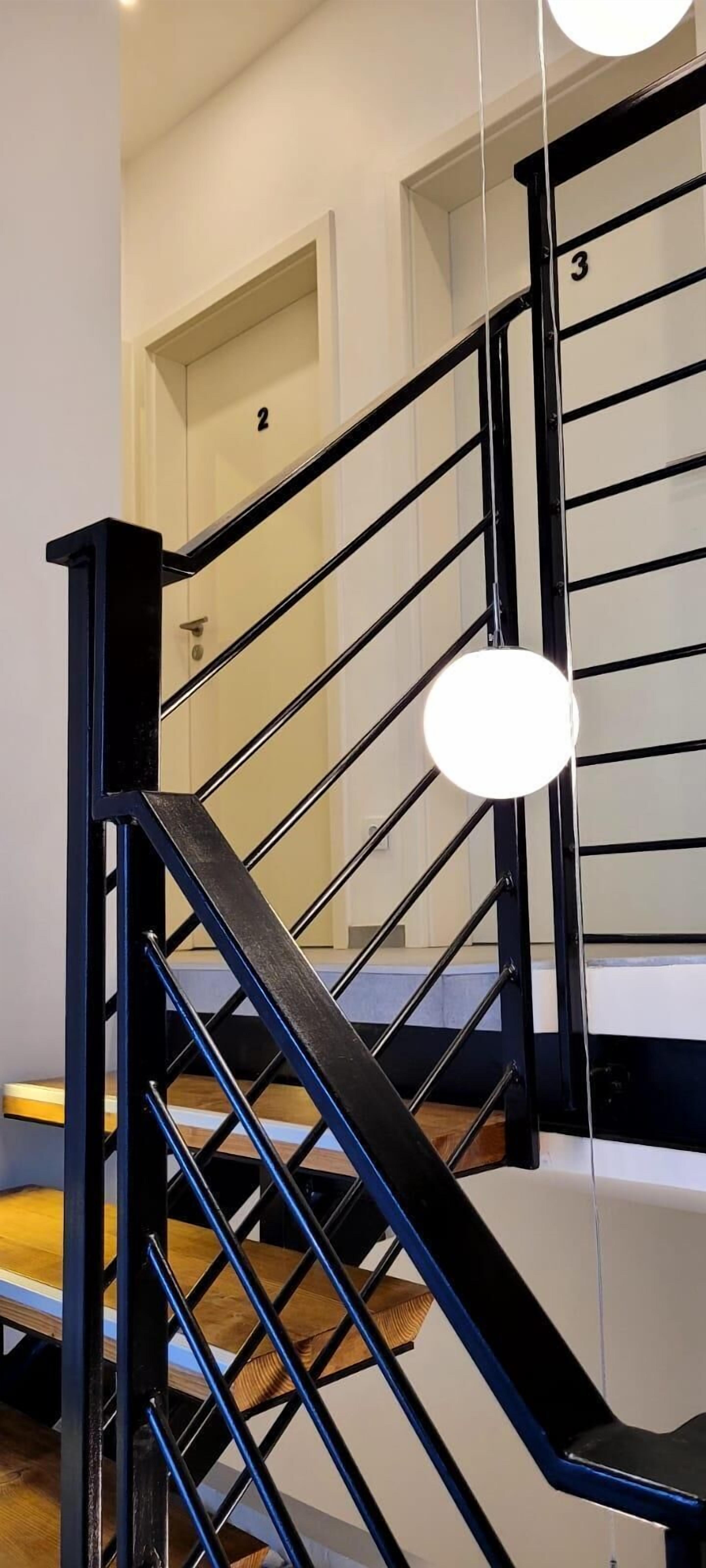 A modern staircase with black railings and wooden steps, leading to a door marked with the number 3.