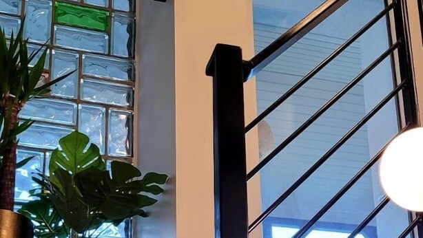 A staircase with a wooden handrail and a view of a window with a plant on the side. - MoselVilla No 7 (Pommern)