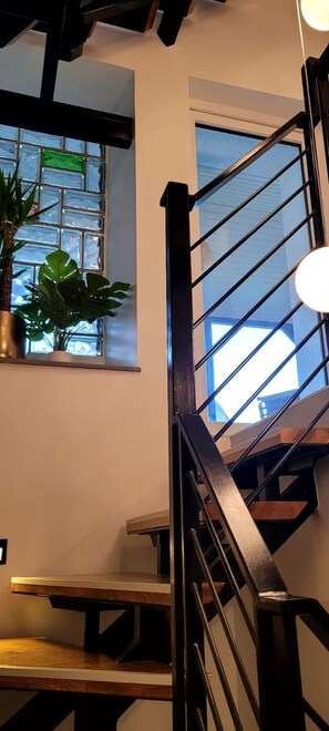 A staircase with a metal railing, a potted plant, and a window with a view of the sky. - MoselVilla No 7 (Pommern)