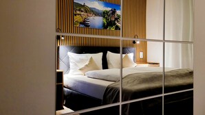 A hotel room with a bed, pillows, a nightstand, and a painting on the wall. - MoselVilla No 7 (Pommern)