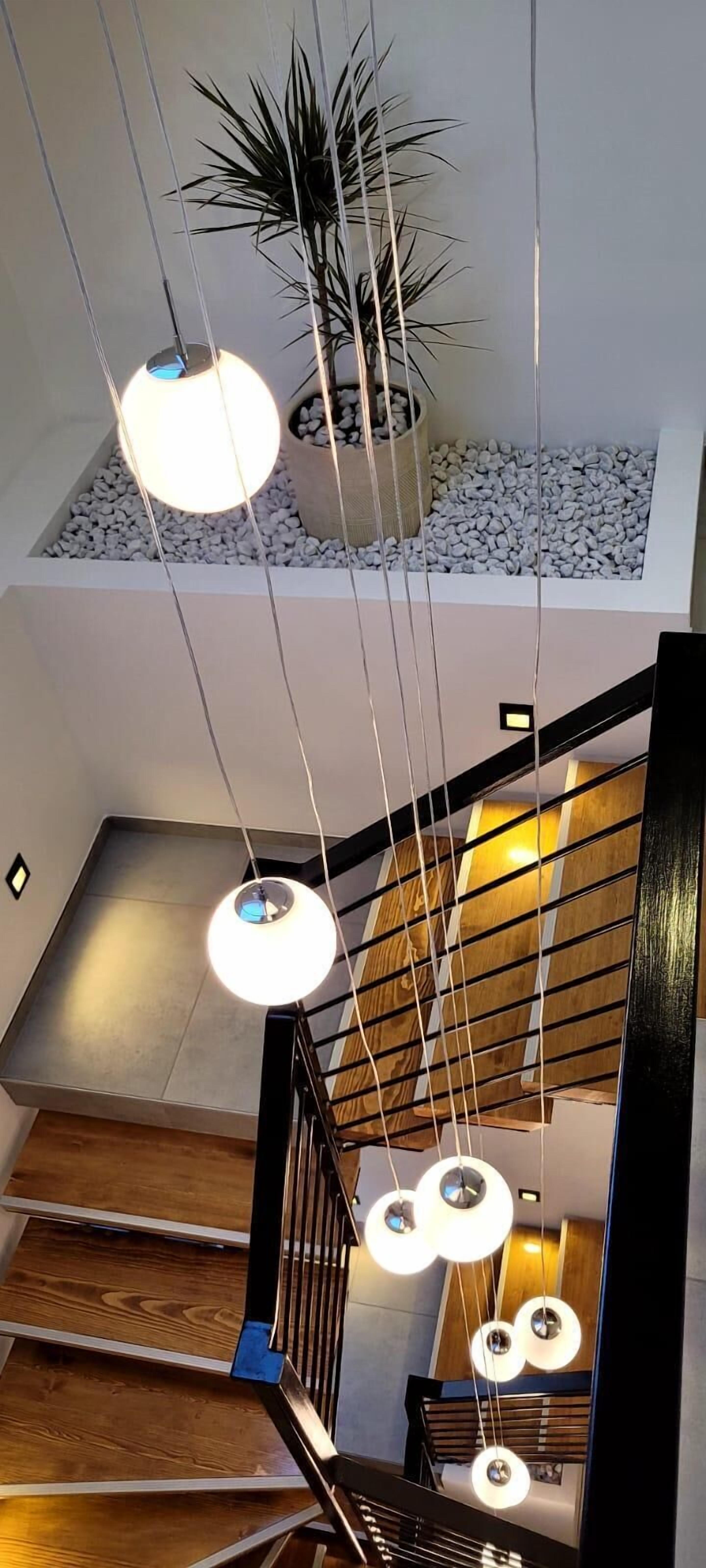 A staircase with a wooden railing and hanging spherical pendant lights.
