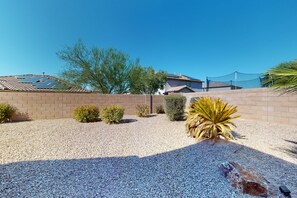 Enjoy a serene outdoor space with a gravel driveway, brick entrance, and lush greenery.
