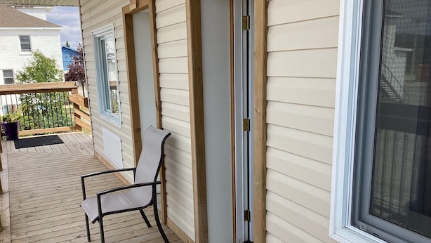 Un pontile in legno con una sedia e un'uscita che dà su un portico coperto.
