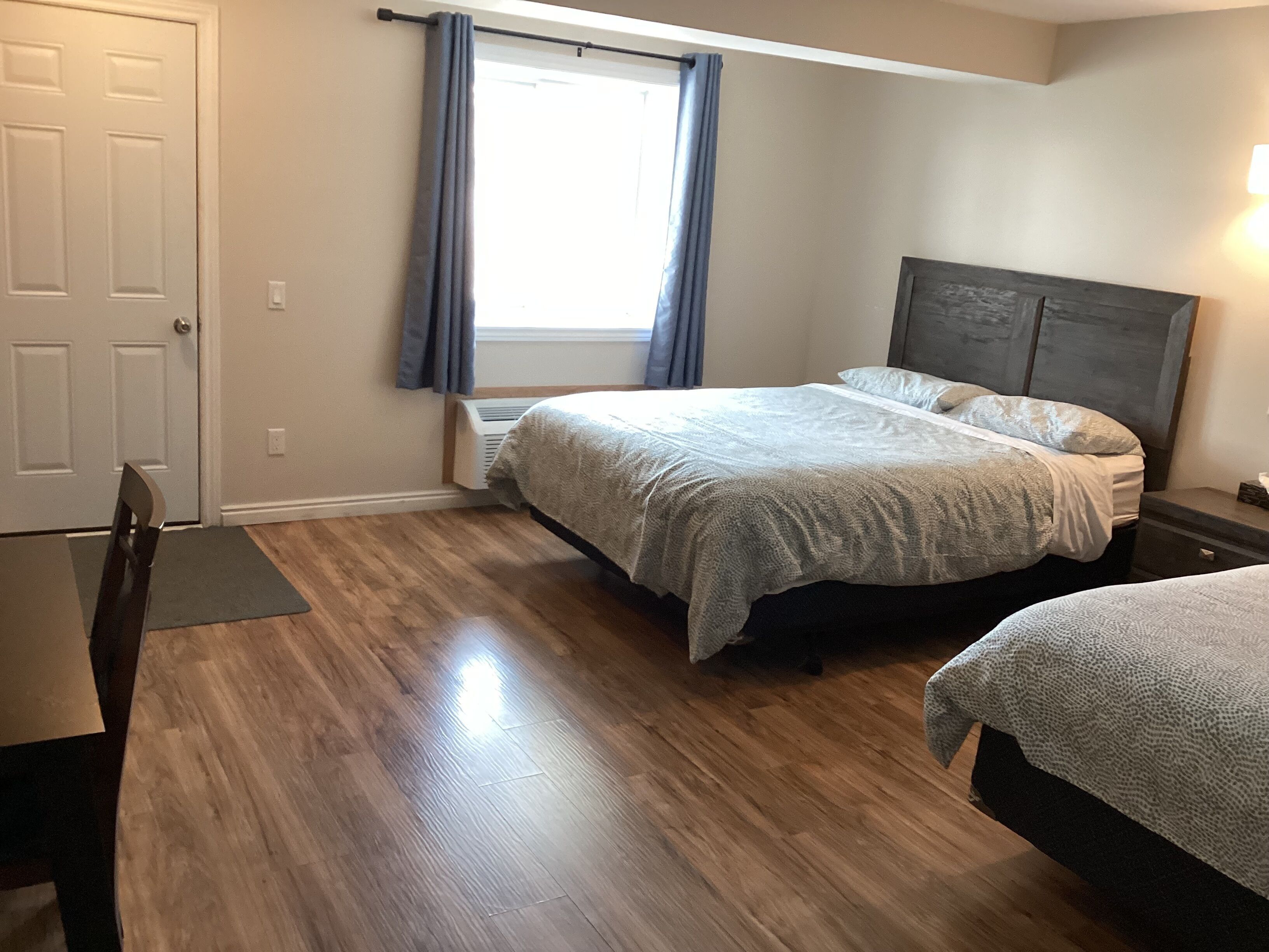 Une chambre à coucher avec un lit, une table de chevet, une chaise et une fenêtre avec des rideaux.