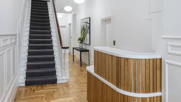 A reception area with a wooden reception desk, a staircase with black carpeted steps, and a herringbone wood floor.