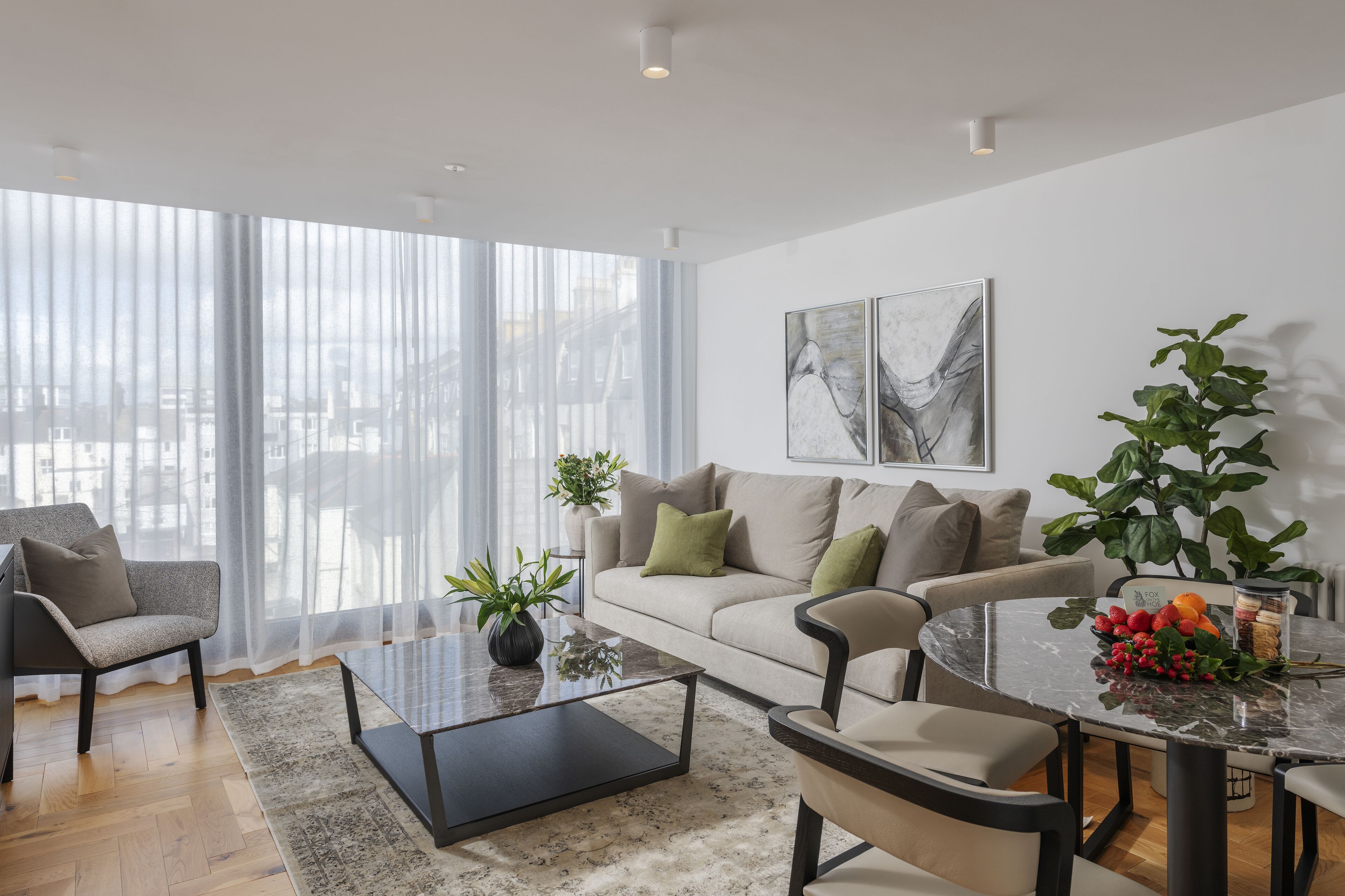A modern living room with a sofa, armchairs, a coffee table, and a dining table.