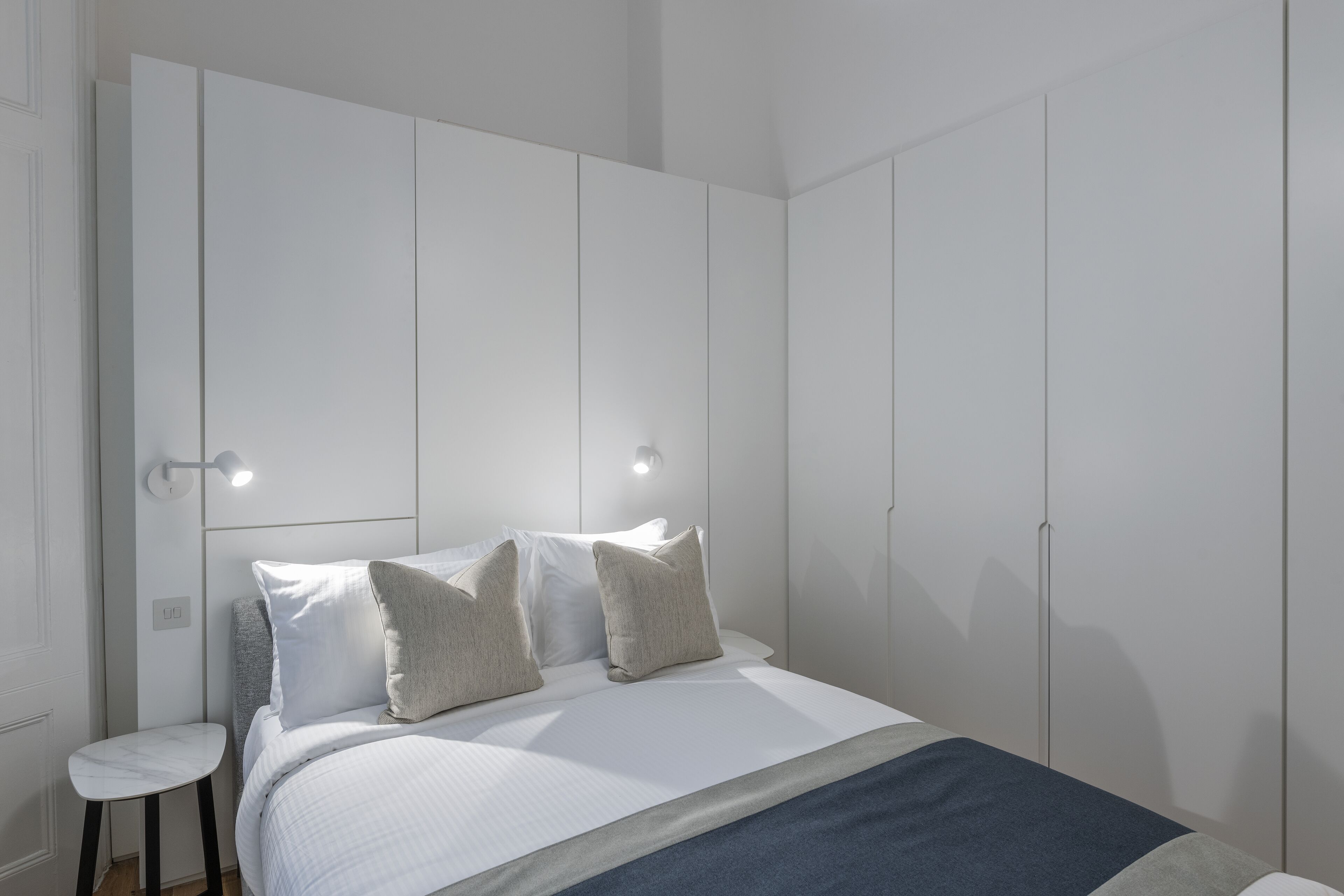 A bedroom with a bed, two bedside tables, and a wardrobe.