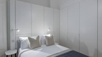 A bedroom with a bed, two bedside tables, and a wardrobe.