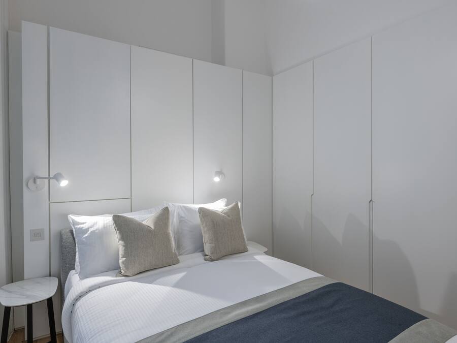 A bedroom with a bed, two bedside tables, and a wardrobe.