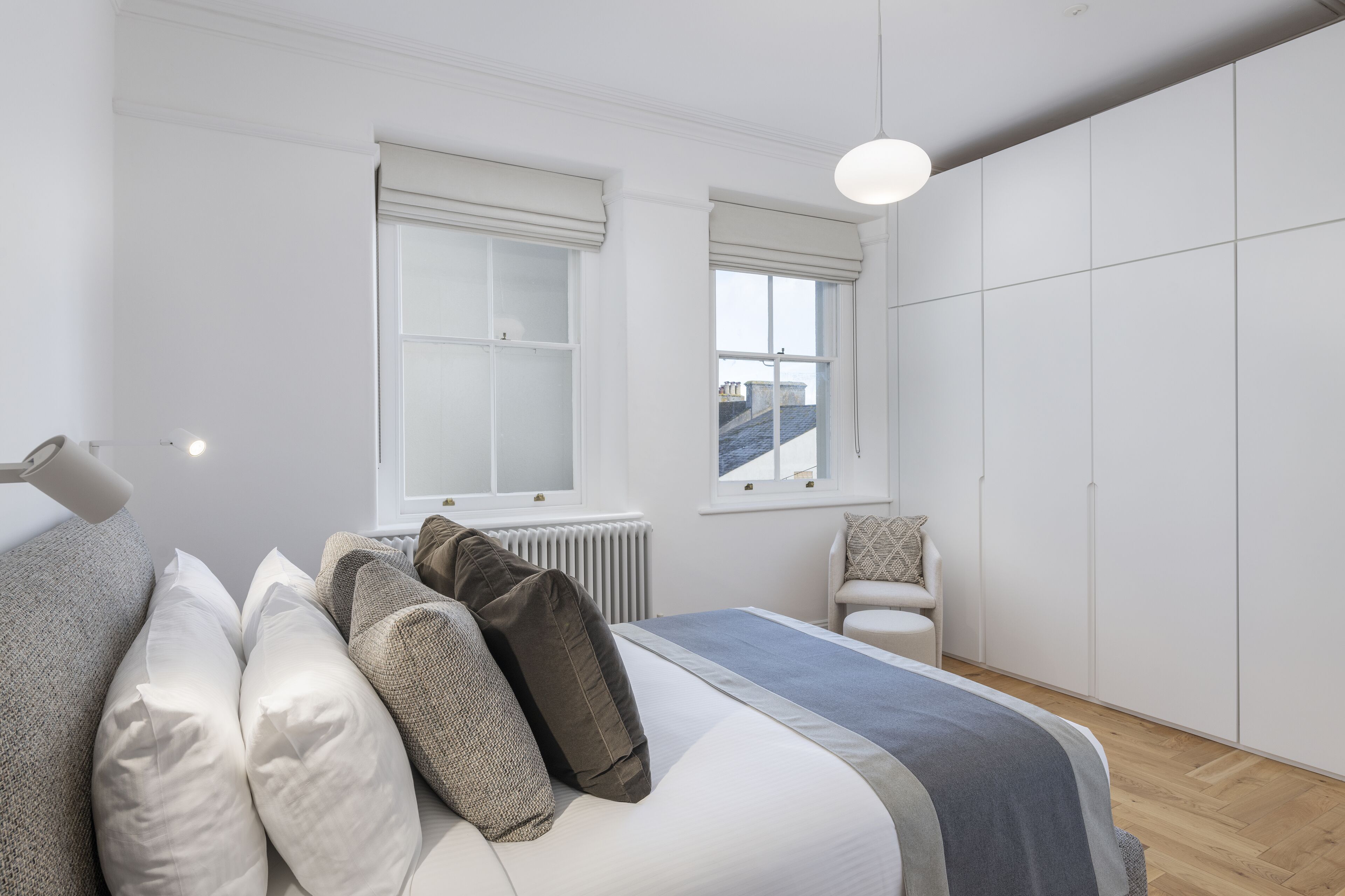 Ein modernes Schlafzimmer mit Bett, Nachttischen, Heizkörper und Kleiderschrank.