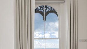 Un baño moderno con una bañera independiente, un ventanal con vistas al mar y suelo de madera.