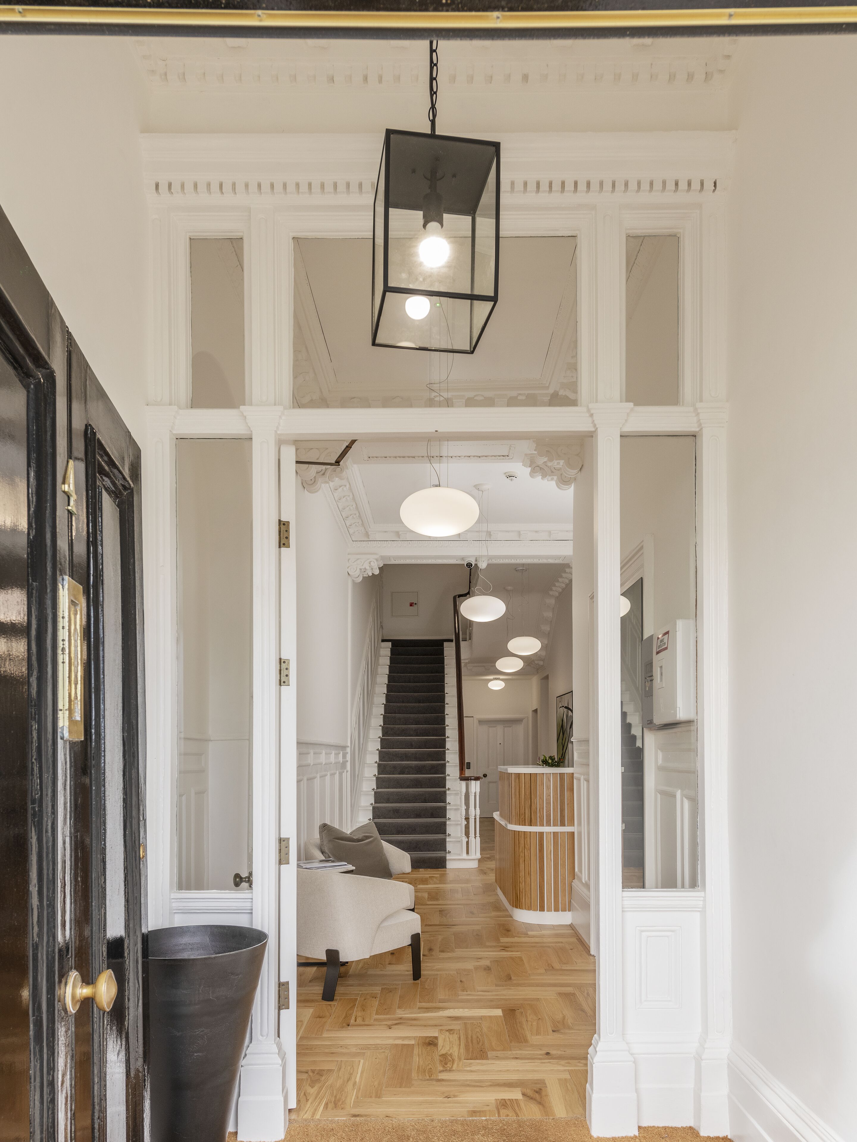 A hallway with a staircase, a reception desk, and a seating area with a sofa.