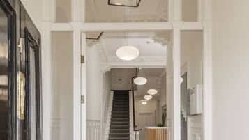 A hallway with a staircase, a reception desk, and a seating area with a sofa.